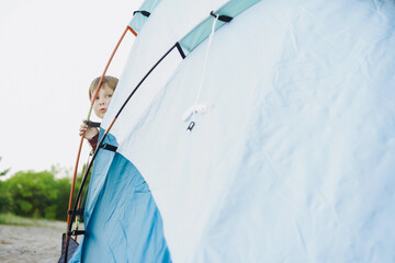cute little caucasian boy looking out from touristic tent. Family camping concept