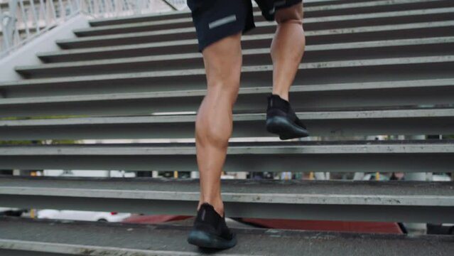 Man rushing up stairs while running late to a fitness training session in the city alone. One sporty and fit male athlete doing a routine outdoor cardio workout on steps while preparing for a race
