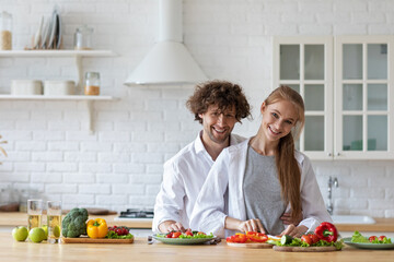 Happy beautiful young couple cooking in the kitchen and having fun together