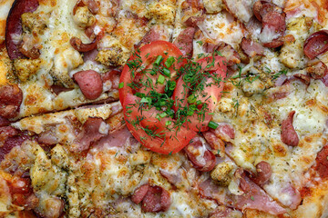 Obraz na płótnie Canvas Pizza with meat sausage and chicken, cheese and tomatoes on a gray concrete background, with selective focus