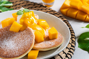 Delicious Japanese souffle pancake with dice mango and jam on white table background.