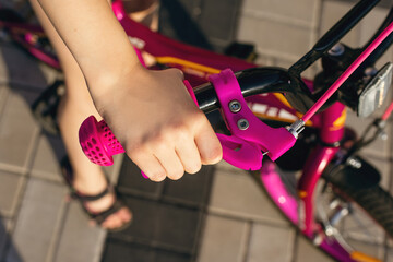 Handbrake on a pink children's bike close-up. The child's hand presses the handbrake. Bike safety...