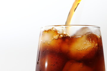 氷の入ったグラスに注ぐコーラ