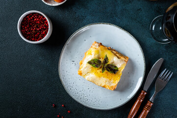 Piece of tasty hot lasagna on dark background. Traditional italian lasagna. Italian food. Close up lasagna. Bolognese sauce. Bechamel sauce. Still life of food. Homemade meat lasagna.
