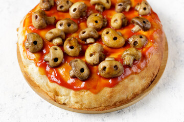 Homemade pizza with tomato sauce and mushrooms in the form of skulls. Concept for Halloween celebrations