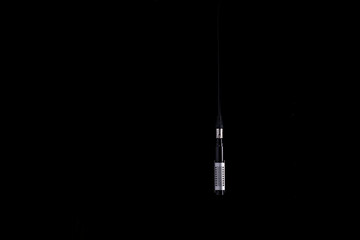 A ribbon microphone hanging from an XLR cable on a black background Nr.1
