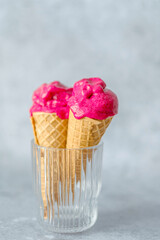 Vegan beetroot ice cream with banana, frozen avocado, coconut milk in a waffle cone in a glass on a gray background