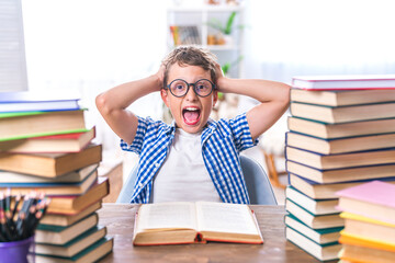 schoolboy tired of learning, wearing glasses, doing homework, sitting indoors between stacks of books. child screams emotionally, indignant because of large amount of homework. Doesn't want to study.