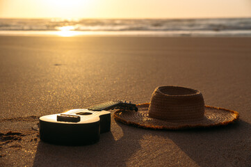 Ukulele and straw hat on sandy beach