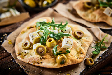 Delicious homemade pizza with olives rucola and cheese served on board