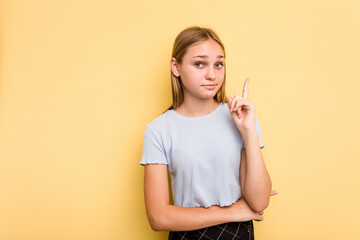 Young caucasian girl isolated on yellow background showing number one with finger.