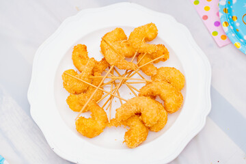 deep-fried shrimp on skewers in a white plate.