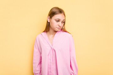 Young caucasian girl isolated on yellow background shrugs shoulders and open eyes confused.