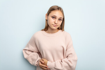 Young caucasian girl isolated on blue background having a liver pain, stomach ache.