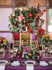 Exotic wedding banquet table decor in purple. Tropical flowers decor, purple wine glasses, crockery, cutlery.