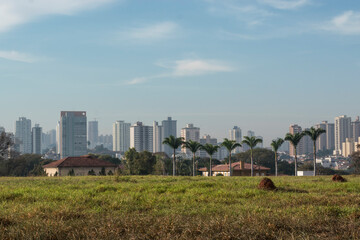 Fototapeta premium Paisagem urbana ,muitos edifícios ,casas térreas ,palmeiras e um terreno gramado.