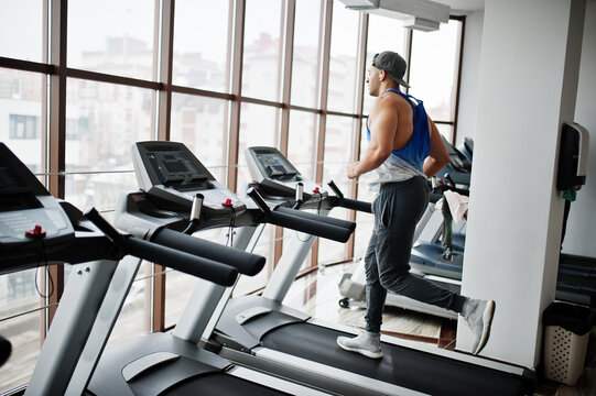 Fit and muscular arabian man running on treadmill in gym.