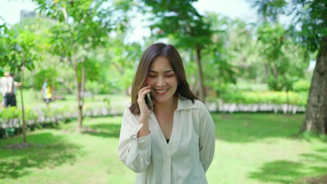 Pretty attractive woman standing and walking in the garden. Girl using smartphone with smile on sunny day. Happiness during vacation. Relaxation, Aromatherapy freedom feeling lifestyle