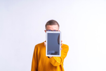 Portrait attractive guy using a 5g app to search the internet, standing on white background. modern teenage student with glasses demonstrate screen of a tablet PC computer. concept of digitalization