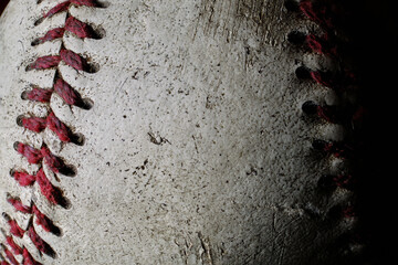Fototapeta na wymiar An old baseball showing authentic wear and tear in extreme closeup with dynamic lighting