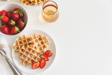 Belgian waffles with strawberry and powdered sugar on white plate. Breakfast food concept. Copy space. Top view