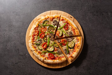 Vegetarian pizza with zucchini, tomato, peppers and mushrooms on black stone background	