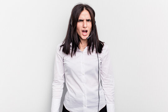 Telemarketer caucasian woman working with a headset isolated on white background screaming very angry and aggressive.