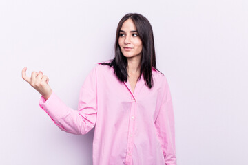 Young caucasian woman isolated on pink background pointing with finger at you as if inviting come closer.
