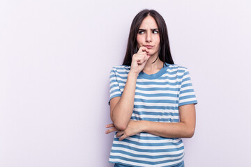 Young caucasian woman isolated on pink background looking sideways with doubtful and skeptical expression.