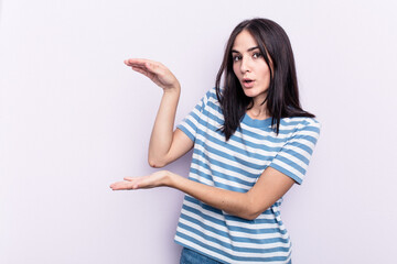 Young caucasian woman isolated on pink background shocked and amazed holding a copy space between hands.