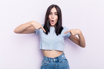 Young caucasian woman isolated on pink background points down with fingers, positive feeling.