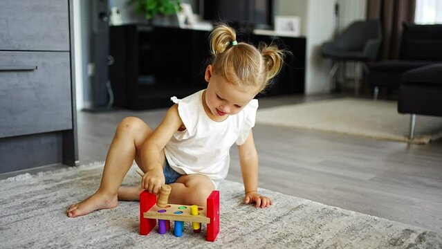 Cute caucasian little girl playing on the floor at home with eco wooden toys. Montessori toy. The child playing educational games.