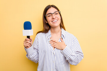 Young caucasian presenter TV woman isolated on yellow background laughs out loudly keeping hand on chest.