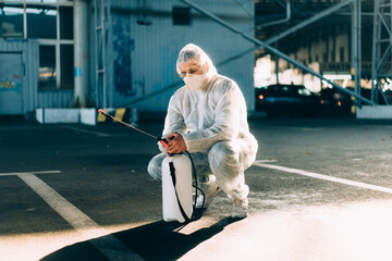 Man dressed white protective overalls spraying surface antibacterial sanitizer sprayer during...