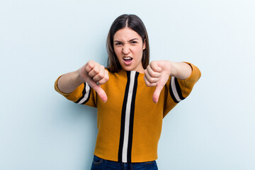 Young caucasian woman isolated on blue background showing thumb down and expressing dislike.