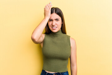 Young caucasian woman isolated on yellow background forgetting something, slapping forehead with palm and closing eyes.