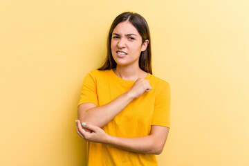 Young caucasian woman isolated on yellow background massaging elbow, suffering after a bad movement.