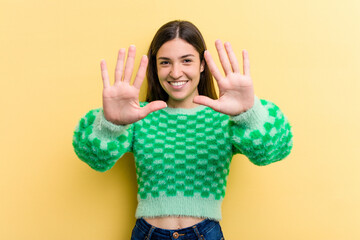 Young caucasian woman isolated on yellow background showing number ten with hands.