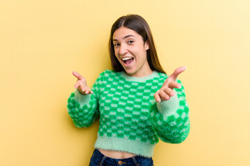 Young caucasian woman isolated on yellow background feels confident giving a hug to the camera.