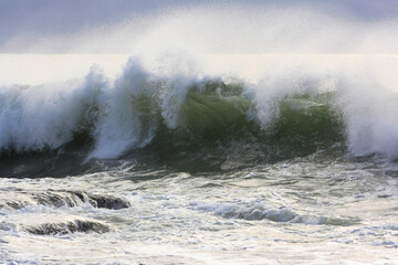 ocean wave breaking on stormy windy summers day with spray flying in the wind