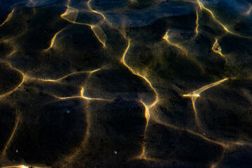 Texture of the water surface. Reflection of light in water, Dark background, Golden lines