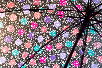 detail of a black umbrella with multi-colored spheres on a white textile background