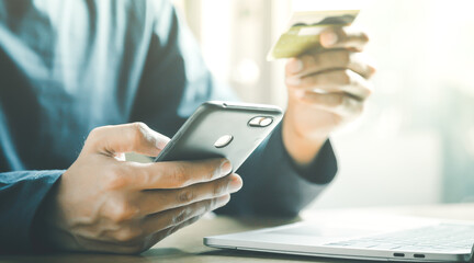 Man holding credit card and using smartphone at home online shopping ecommerce internet banking spend money work from home concept.