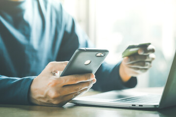Man holding credit card and using smartphone at home online shopping ecommerce internet banking spend money work from home concept.
