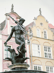 Obraz premium Neptune Fountain in front of a colorful building in Gdansk Poland. Concept of travel destination in eastern Europe.