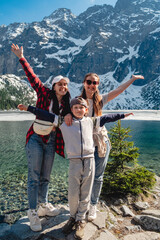 A family are standing on the shore of a lake. Morskie Oko, Tatras mountains.