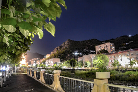 Night city from a bird's eye view. The light of houses and cars. A beautiful city with rivers, bridges and beautiful buildings. City among the mountains, Kapan, Armenia
