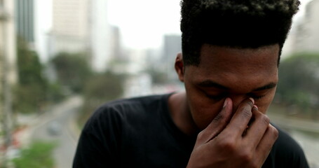 Obraz premium Frustrated young black African man standing outside in city