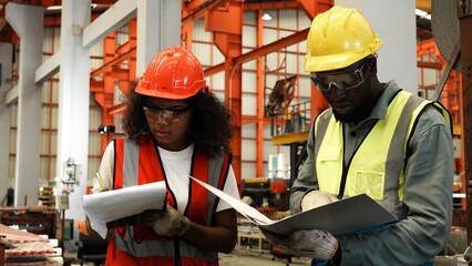 Two engineer worker together, Woman talking and pointing with Man. Two people wear safety uniform...