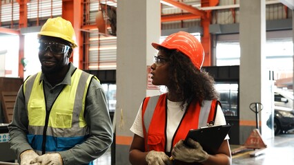 Two engineer worker together, Woman talking and pointing with Man. Two people wear safety uniform...
